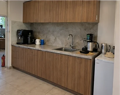 Office kitchen with wood-effect cabinet fronts and a stone-effect splashback